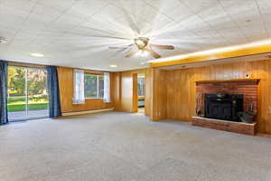 Living room featuring wood walls, carpet floors, and a baseboard heating unit