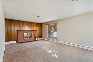 Living room featuring baseboard heating, wooden walls, and a fireplace