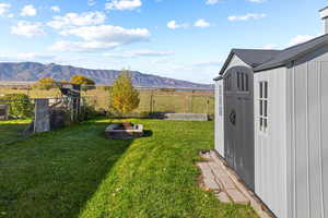 View of yard with a storage unit, a mountain view, and a fire pit