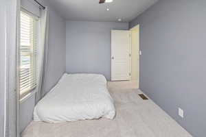 Bedroom with ceiling fan and light carpet