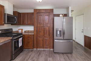 Kitchen featuring appliances with stainless steel finishes, wood-type flooring, and dark stone counters