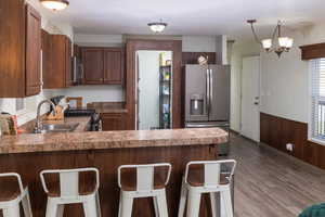 Kitchen featuring kitchen peninsula, stainless steel appliances, a kitchen bar, and hanging light fixtures