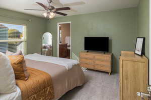 Carpeted bedroom featuring ceiling fan and ensuite bath