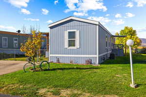 View of side of property featuring a lawn and cooling unit