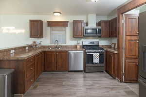 Kitchen featuring light hardwood / wood-style flooring, stainless steel appliances, dark brown cabinets, and sink