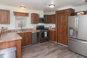 Kitchen featuring appliances with stainless steel finishes, sink, and light wood-type flooring