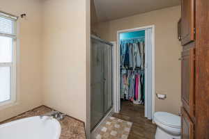 Bathroom with shower with separate bathtub, wood-type flooring, and toilet