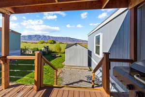 Wooden deck with a mountain view, a storage unit, a rural view, and a lawn