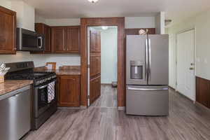 Kitchen featuring light hardwood / wood-style floors, appliances with stainless steel finishes, and dark stone counters