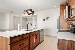 Kitchen featuring a sink, stainless steel appliances, light countertops, an island with sink, and recessed lighting