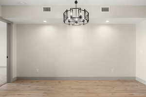 Empty room featuring a chandelier, light wood finished floors, a smoke detector, recessed lighting, and baseboards