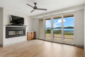Unfurnished living room featuring light wood-type flooring, a high end fireplace, a ceiling fan, and baseboards
