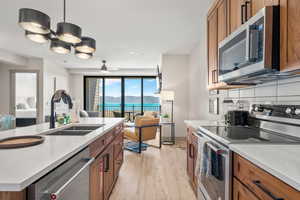 Kitchen with stainless steel appliances, a sink, brown cabinetry, open floor plan, and light wood-style floors