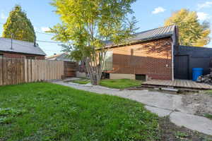 Back of house with a deck and a yard