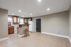 ADU Kitchen with white appliances, sink, a breakfast bar area, and a kitchen island