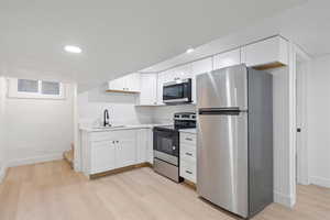 Kitchen featuring sink, white cabinetry, stainless steel appliances, and light wood-type flooring