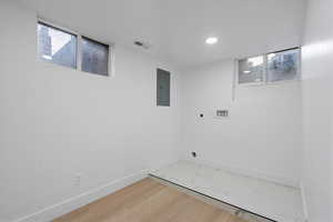 Laundry room featuring hookup for an electric dryer, hardwood / wood-style floors, a healthy amount of sunlight, and electric panel