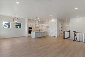 Unfurnished living room featuring a chandelier and light wood-type flooring