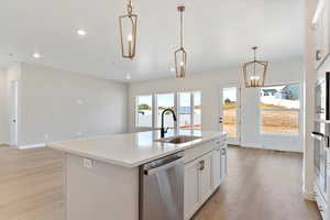 Kitchen with hanging light fixtures, a center island with sink, light wood-type flooring, sink, and stainless steel appliances