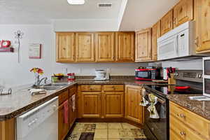 Kitchen with appliances with stainless steel finishes, kitchen peninsula, a textured ceiling, and sink