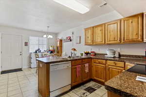 Kitchen featuring kitchen peninsula, dishwasher, a textured ceiling, and a notable chandelier