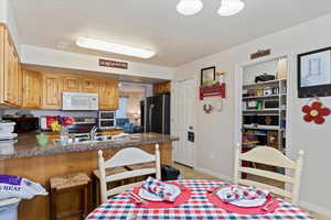 Kitchen with a kitchen bar, a textured ceiling, kitchen peninsula, and stainless steel appliances