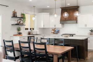 Kitchen with a center island, hardwood / wood-style floors, white cabinetry, decorative light fixtures, and a breakfast bar