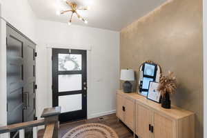 Entryway featuring a notable chandelier and dark wood-type flooring