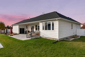 Back house at dusk with a patio and a yard