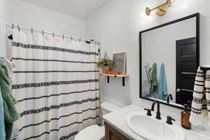 Bathroom with vanity, curtained shower, and toilet