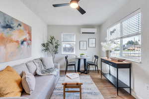 Living room with light hardwood / wood-style flooring, a textured ceiling, a wall mounted mini split with heating and cooling, and ceiling fan