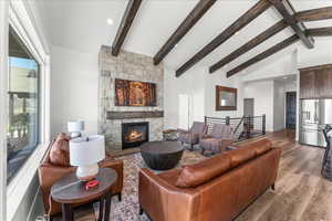 Living room featuring light hardwood / wood-style flooring, vaulted ceiling with beams, and a fireplace