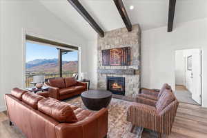 Living room with vaulted ceiling with beams, a mountain view, a fireplace, and light wood-type flooring