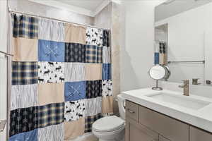 Bathroom with vanity, toilet, and curtained shower