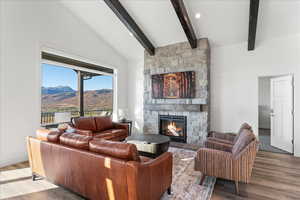 Living room featuring a mountain view, vaulted ceiling with beams, a fireplace, and hardwood / wood-style floors