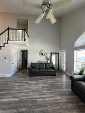 Living room featuring LVP floors, a towering staircase, and ceiling fan