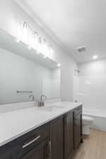 Full bathroom with vanity, a textured ceiling, bathing tub / shower combination, wood-type flooring, and toilet