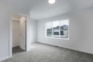 Unfurnished bedroom with carpet floors, a spacious closet, and a closet