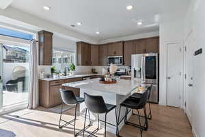 Kitchen featuring a kitchen island, appliances with stainless steel finishes, a breakfast bar, light wood-type flooring, and sink