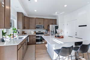 Kitchen featuring a center island, appliances with stainless steel finishes, a breakfast bar area, and light wood-type flooring