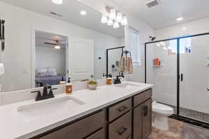 Bathroom featuring vanity, toilet, and a shower with door