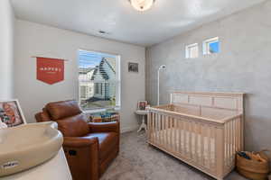 Carpeted bedroom featuring a crib