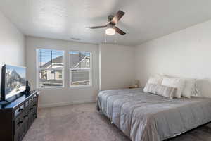 Bedroom with light carpet, a textured ceiling, and ceiling fan