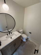 Bathroom with vanity, toilet, and concrete flooring