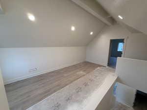 Bonus room featuring light hardwood / wood-style floors and vaulted ceiling with beams