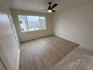 Empty room featuring a textured ceiling, light wood-type flooring, and ceiling fan