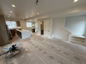 Interior space with a kitchen island, light stone countertops, and an inviting chandelier