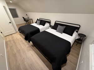 Bedroom featuring light wood-type flooring and vaulted ceiling