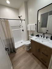 Bathroom with toilet, vanity, and a shower with shower curtain