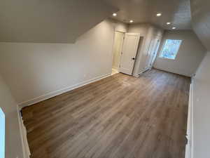 Additional living space with lofted ceiling, hardwood / wood-style floors, and a textured ceiling